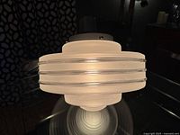 Front and side view of the vintage Art Deco style ceiling lamp showing frosted glass with clear banding and metallic trim attached to ceiling mount.