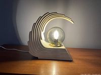 Side view of the vintage wave lamp turned on showing layered wave sculptural design and illuminated globe bulb.
