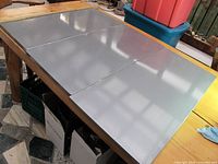 Three silver metal magnet boards laid out on a table, showing size and surface.