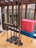 Metal candle sticks arranged by height on a wooden table with a ruler for size reference. Tallest is about 30 inches.
