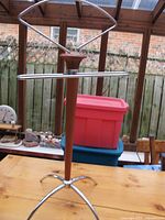 Full view of the silent butler clothes stand on wooden table in a conservatory.