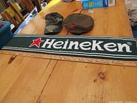 Photo showing two hats and a Heineken scarf laid out on wooden table.