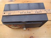 Front and top view of the vintage General Electric radio showing the black Bakerlight plastic body, circular tuning dial, and tuning knob with a ruler for size reference.