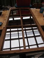 Full view of vintage window mirror laying flat showing wooden frame and reflected ceiling grid.