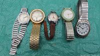 Full view of all six wristwatches showing various band types and dial designs.