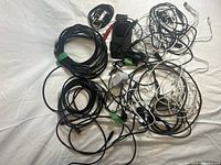 Wide view of assorted cables and chargers laid out on a white surface including black and white cables coiled and loose.
