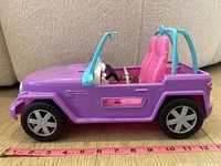 Side view of Barbie Jeep showing purple body, pink seats, blue roll bars, and wheels next to measuring tape for scale.
