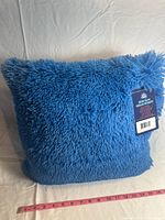 Blue square shaggy textured pillow showing front and size measurement with a tape measure in inches.