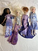 Four Disney Princess dolls arranged side by side on a surface, showing full length of dolls and dresses.