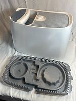 Front side view of the white Honeywell humidifier with blue handle and top grid air output.