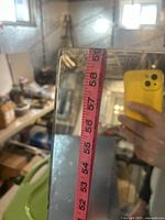 Close-up photo showing the top edge of the mirror with measuring tape reflecting 59 inches in height.