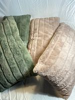 Four faux fur throw pillows, two green and two pink, displayed together on white fabric background.