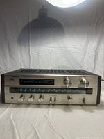 Front full view of Sony STR-V2 stereo amplifier and receiver sitting against white cloth background showing power button, tuning meters, and control knobs.