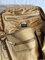 Interior view of tan faux leather duffel bag showing zippered pocket and Bueno brand tag inside.