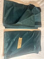 Two folded dark green velvet curtain panels with discreet dotted pattern, size label visible stating 2 x 48" x 84"