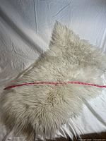 Photo showing full white faux fur rug with a measuring tape across the length indicating approximately 36 inches.