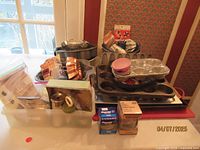 Full lot contents including various baking pans, molds, cookie cutters, baking cups, and related baking tools arranged on a table.
