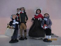Group shot of the four Byer's Carolers in traditional clothing on black bases, arranged in a line.