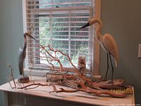 Overview of two heron sculptures, driftwood, seashell vase and branch decor on tabletop