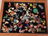 Top-down view of assorted vintage Cracker Jack charms arranged inside the wooden display case showing a variety of shapes and colors.
