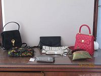 Seven evening purses displayed on a wooden dresser showing variety of colors and styles