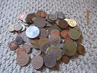 Assorted foreign coins scattered on carpet showing variety of metals and sizes