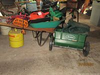 Scotts spreader, weed eater, fuel container, wheelbarrow, and blower shown together