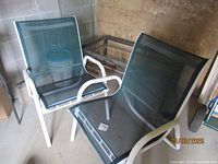Two vintage outdoor patio chairs with white aluminum frames and green sling mesh seating and backs, shown together.