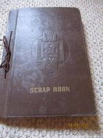 Closed brown scrapbook cover with embossed design and title 'SCRAP BOOK' in gold lettering.