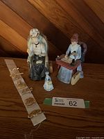 Three Avon Mrs. Albee porcelain figurines and a strip of six gold-tone President's Club pins, all displayed on a wooden surface.