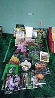 Photo showing an assortment of gardening books arranged on a green surface with cover titles visible including orchids, container gardening, pruning, and others.