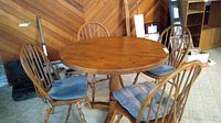 Full view of round wooden kitchen table with four spindle-back chairs and blue cushions around it.