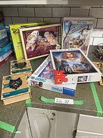 Photo showing multiple boxed jigsaw puzzles including Ravensburger 2000-piece puzzles and wooden Puzzle Art animal puzzles such as owls and wolves arranged on a countertop.