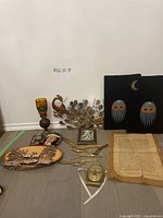 Full view of lot showing all vintage decor items including string art, brass decor, oil lamp, trays, mask and framed poem.