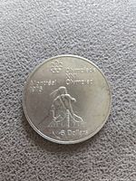 Top side of the coin showing a canoeist image with Olympic branding and $5 denomination