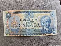 Front side of 1979 Canadian $5 banknote showing portrait of Sir Wilfrid Laurier, Canadian coat of arms, bilingual denomination and security features.