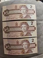 Front sides of three 1986 Canadian $2 banknotes showing Queen Elizabeth II portrait.