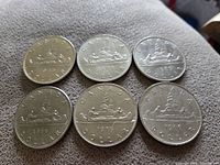 Obverse and reverse views of six Canadian silver dollar coins dated 1969, 1975, and 1986, displayed on a cloth surface.