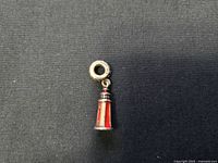 Pandora sterling silver lighthouse charm showing front and side views, highlighting red enamel panels and silver detailing.