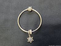 Full view of the sterling silver bracelet with snowflake clasp and dangling snowflake charm with stones.