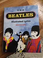 Front cover of The Beatles Illustrated Lyrics book showing colorful illustrated portraits of the band members.