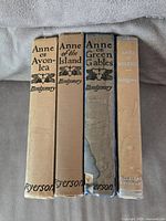 Photo showing the spines of four vintage Anne of Green Gables series books in fabric covers with titles and author names visible.