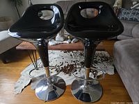 Front view of two black vintage barstools with molded seats and chrome pedestal bases showing their shape and style.