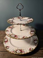 Front view of the three tiered dessert stand showing floral pattern on three plates and metal handle.
