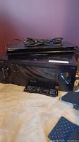 Pioneer Elite receiver with remote on top and Sony Blu-ray player on top of receiver, with cables.