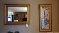 Photo showing the gold color framed rectangular mirror and the gold color framed bamboo print side by side on the wall.