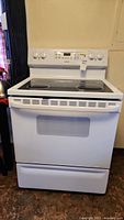 Front view of white Hotpoint stove with glass top and control panel, showing overall condition and design.