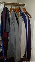 Hanging men's jackets and sweaters in various colors including gray, cream, blue, and purple, with scarves on the left.