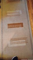 Beige runner rug with rectangular geometric patterns in brown and tan.