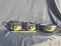 Group view of all four porcelain items on draped backdrop
